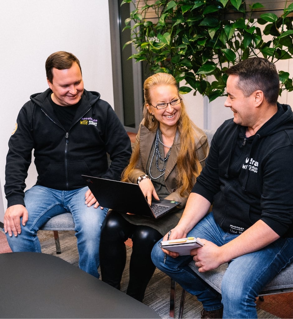 Yrityspalvelut yrittäjyyden kaikkiin vaiheisiin | Business Joensuu | kaksi miestä ja nainen istuvat ja tekevät töitä yhdessä nauraen