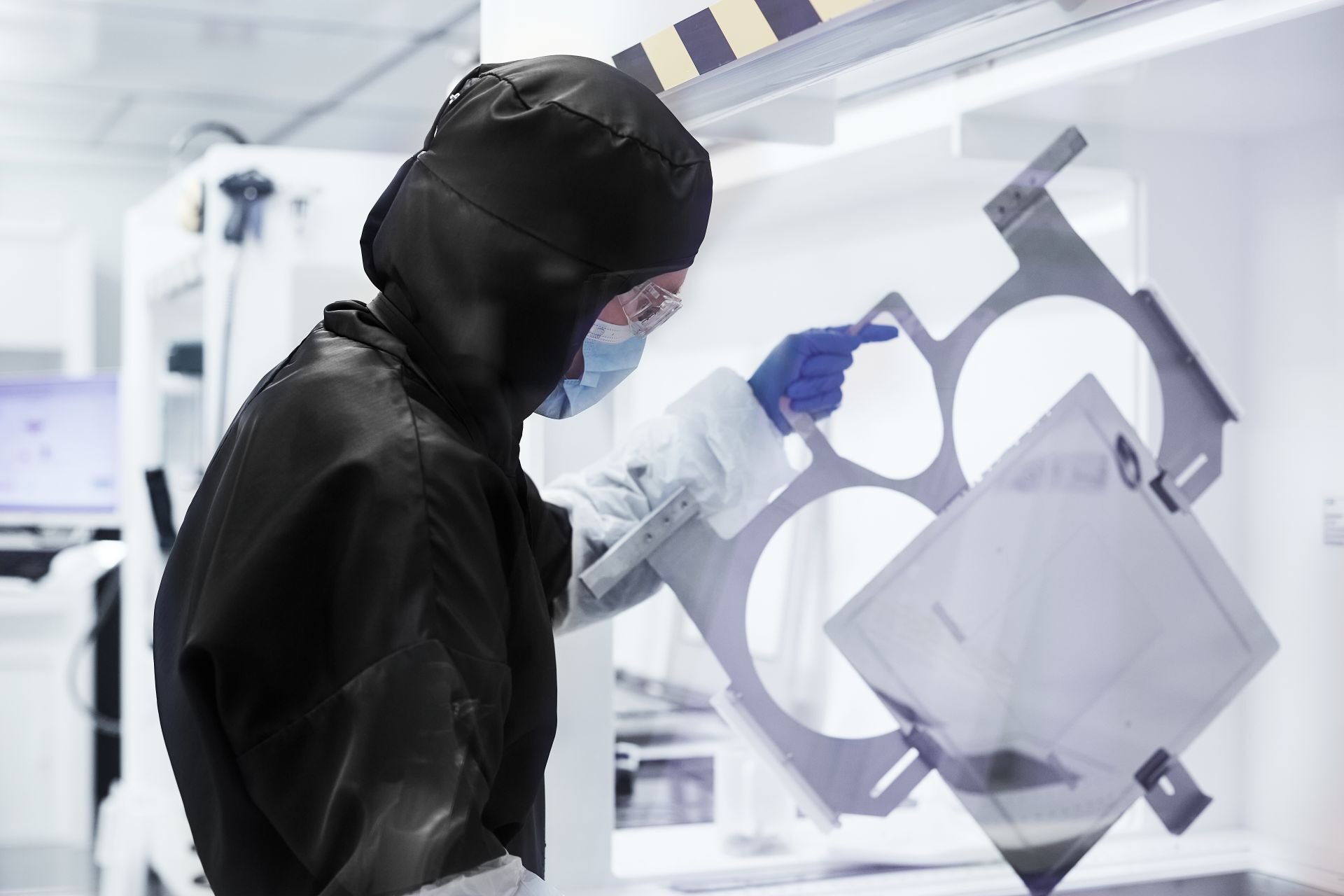 Laboratorioasuun pukeutunut ihminen nostaa muotin näköistä asiaa.