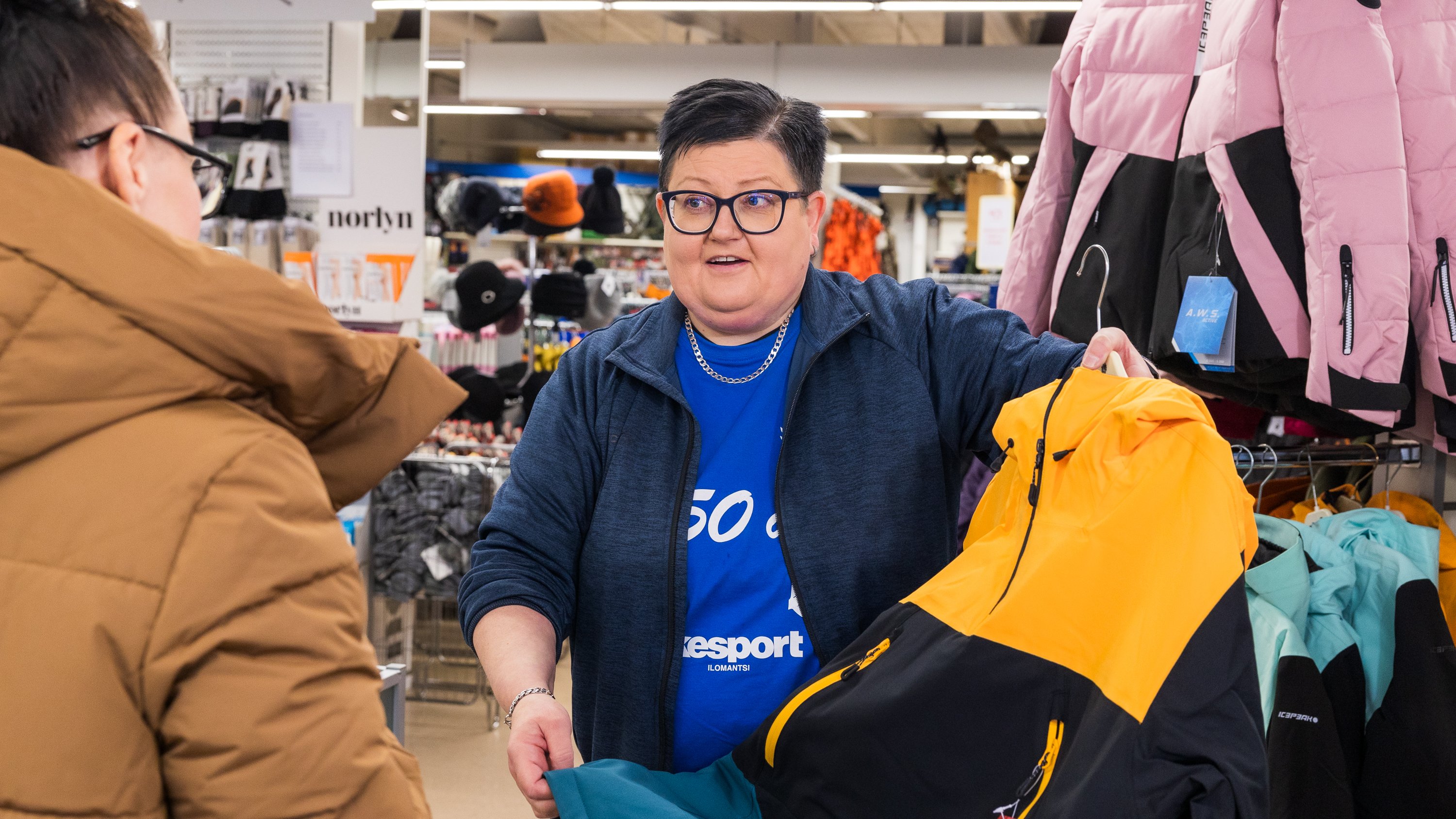 The entrepreneur of Kesport Ilomantsi Heli Kortelainen presents a jacket to a customer | Business Joensuu, business services